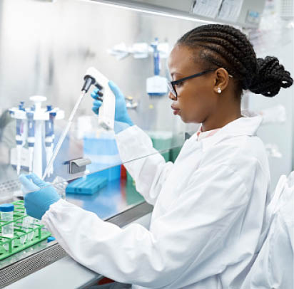Female scientist analyzing medical sample in test tube. Young researcher is wearing lab coat. She is concentrating while working in laboratory.