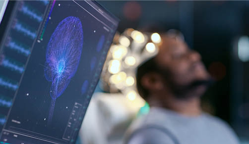 Monitors Show EEG Reading and Graphical Brain Model. In the Background Laboratory Man Wearing Brainwave Scanning Headset Sits in a Chair with Closed Eyes. In the Modern Brain Study Research Laboratory