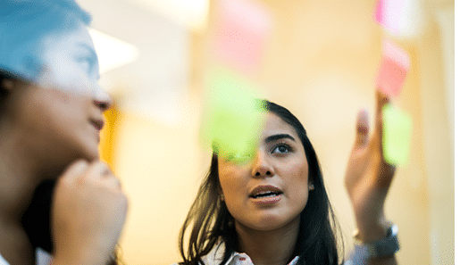 Two business women working together on wall glass