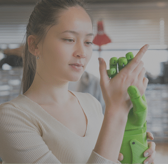 Female engineer examining prosthesis hand project in workshop 
