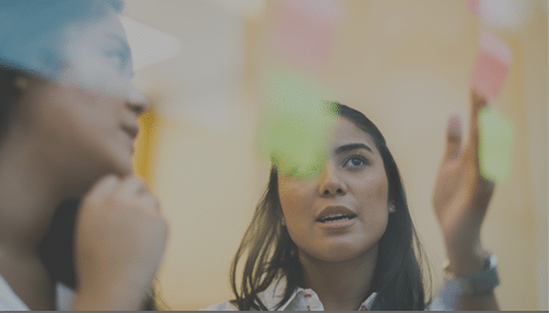 Two business women working together on wall glass