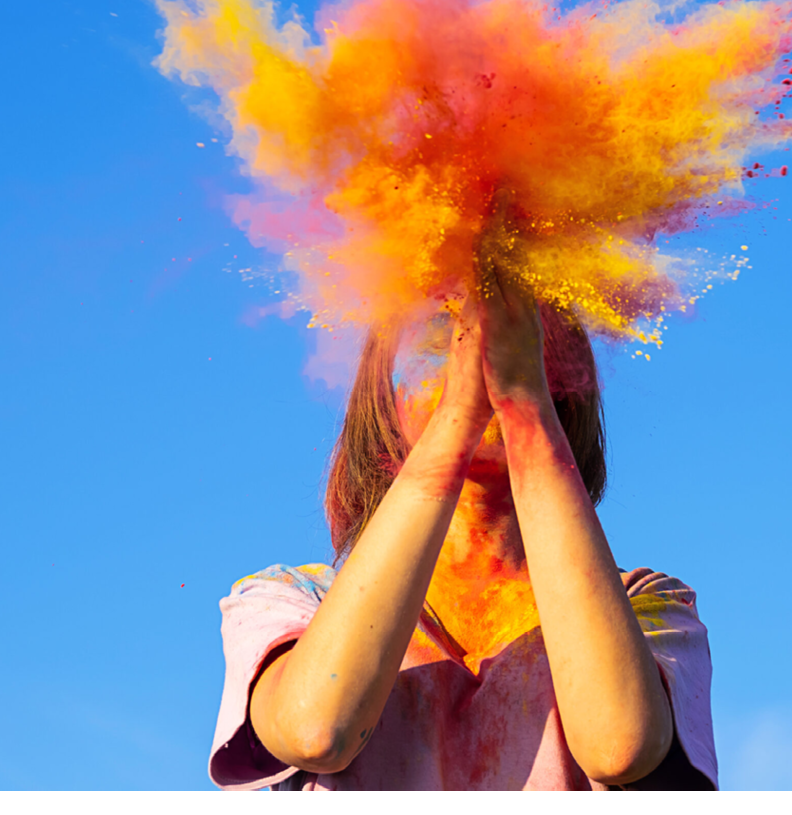 Woman covered in holi powder against blue sky. Holi colours festival.