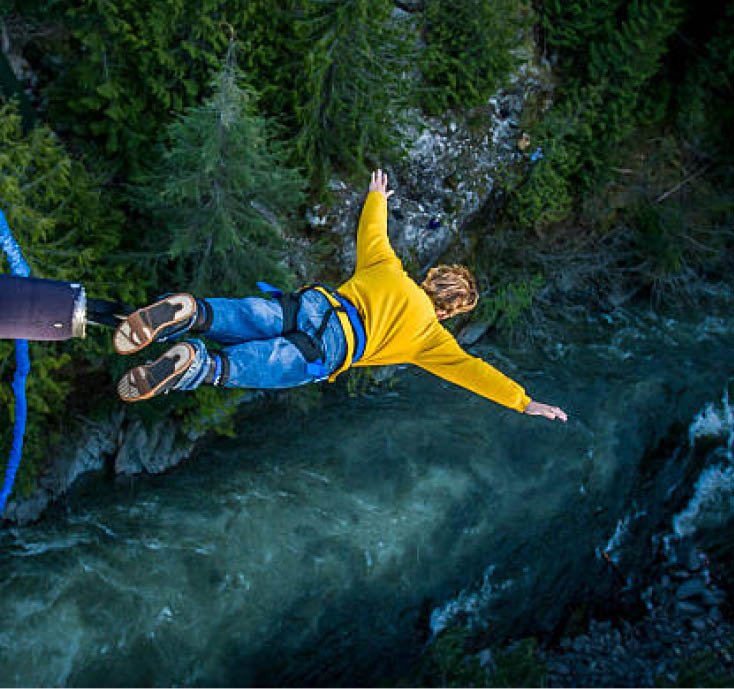 Young man bungee jumping over river.