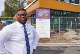 A man in a white shirt and blue tie stands in front of a construction site. AI generated content