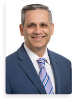 A man wearing a blue suit and a purple tie is smiling for the camera. AI generated content