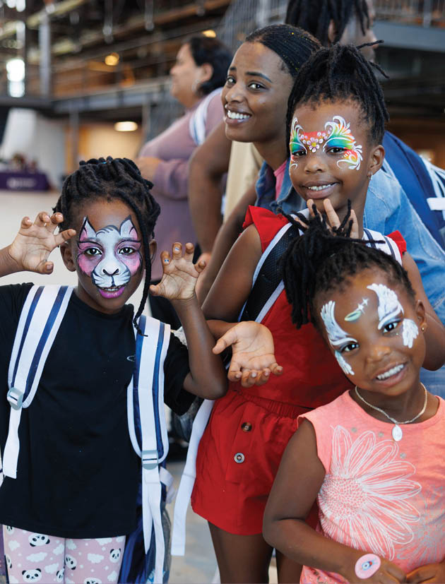 Three children with painted faces and backpacks pose for a picture. AI generated content
