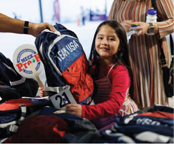 A woman and a girl are looking at shirts at a table. The woman is holding a shirt up for the girl to see. AI generated content