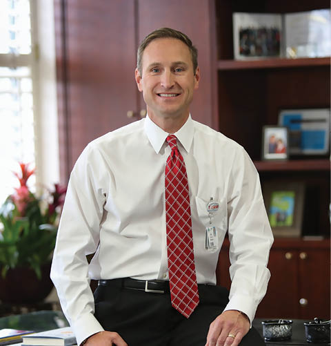 A man in a white shirt and red tie is smiling in an office setting. AI generated content